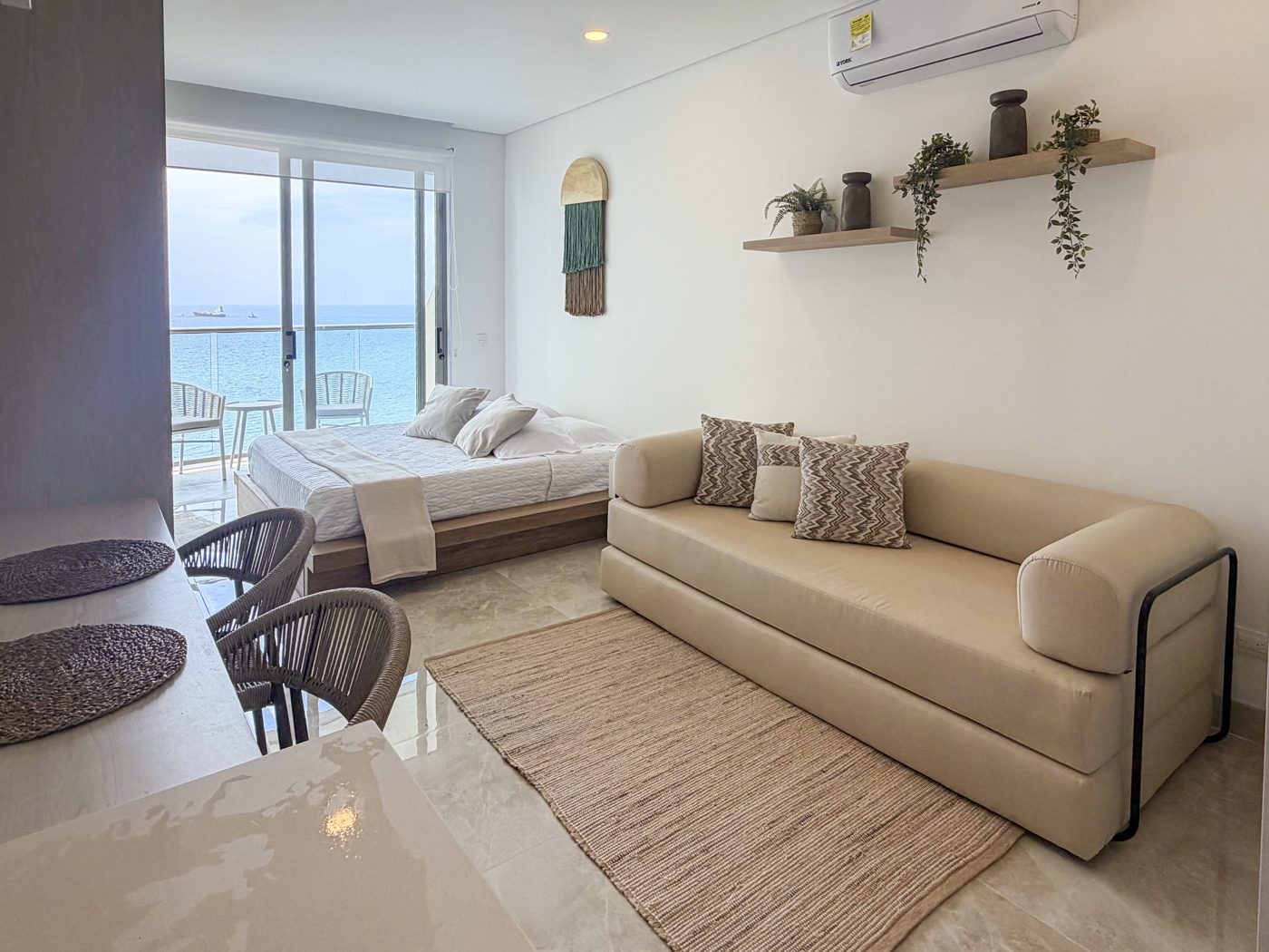 Cama, sofá y comedor frente al mar